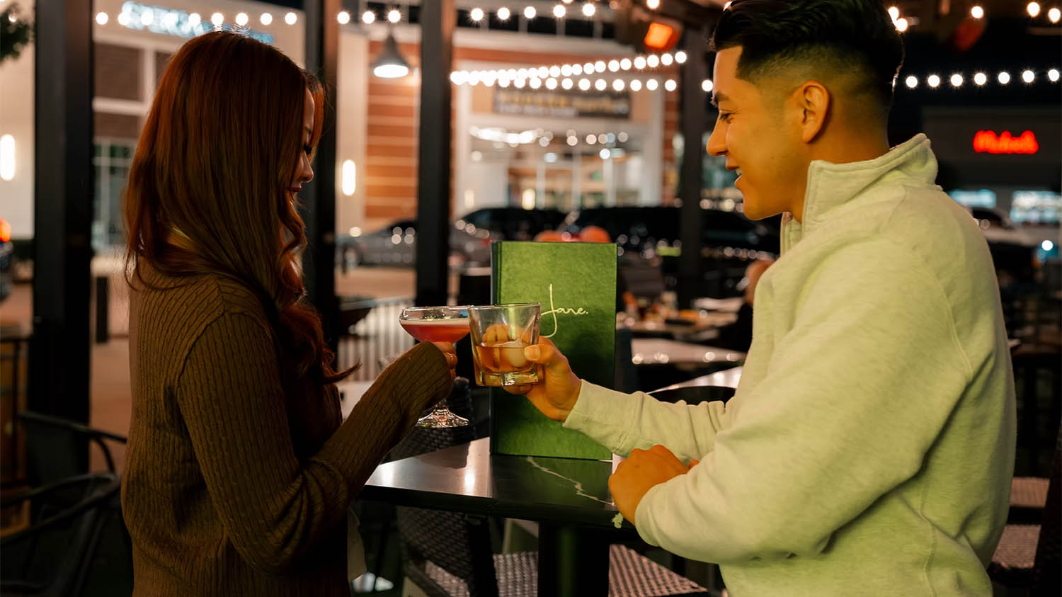 Couple toasting cocktails on the Jane Southlake patio on a date night