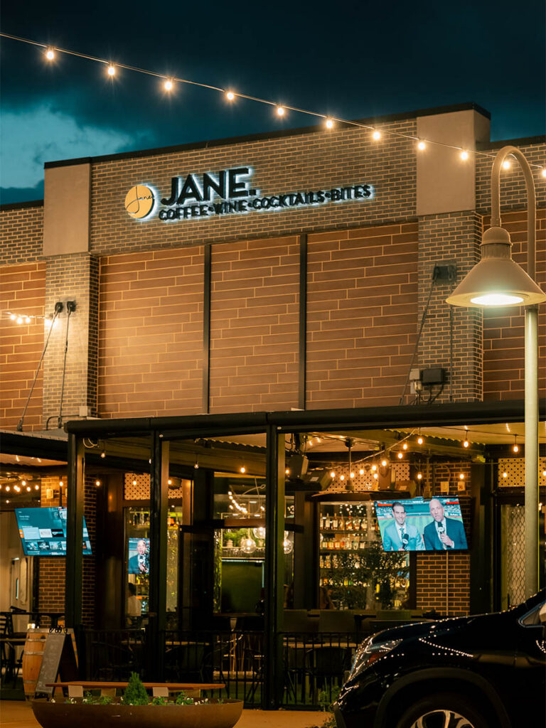 Jane cocktail bar and kitchen exterior at night with string lights in Southlake Texas