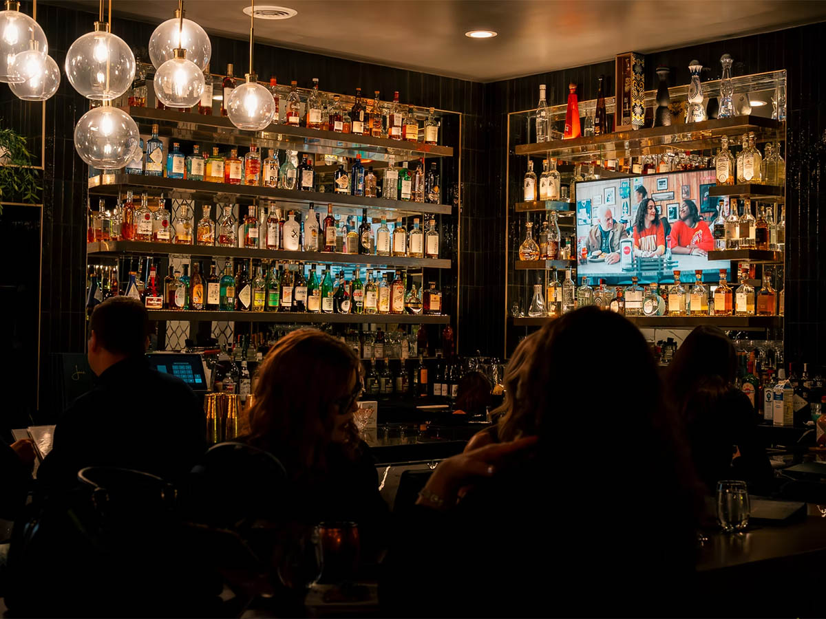 Full liquor wall and globe pendant lighting at the Jane Southlake cocktail bar interior